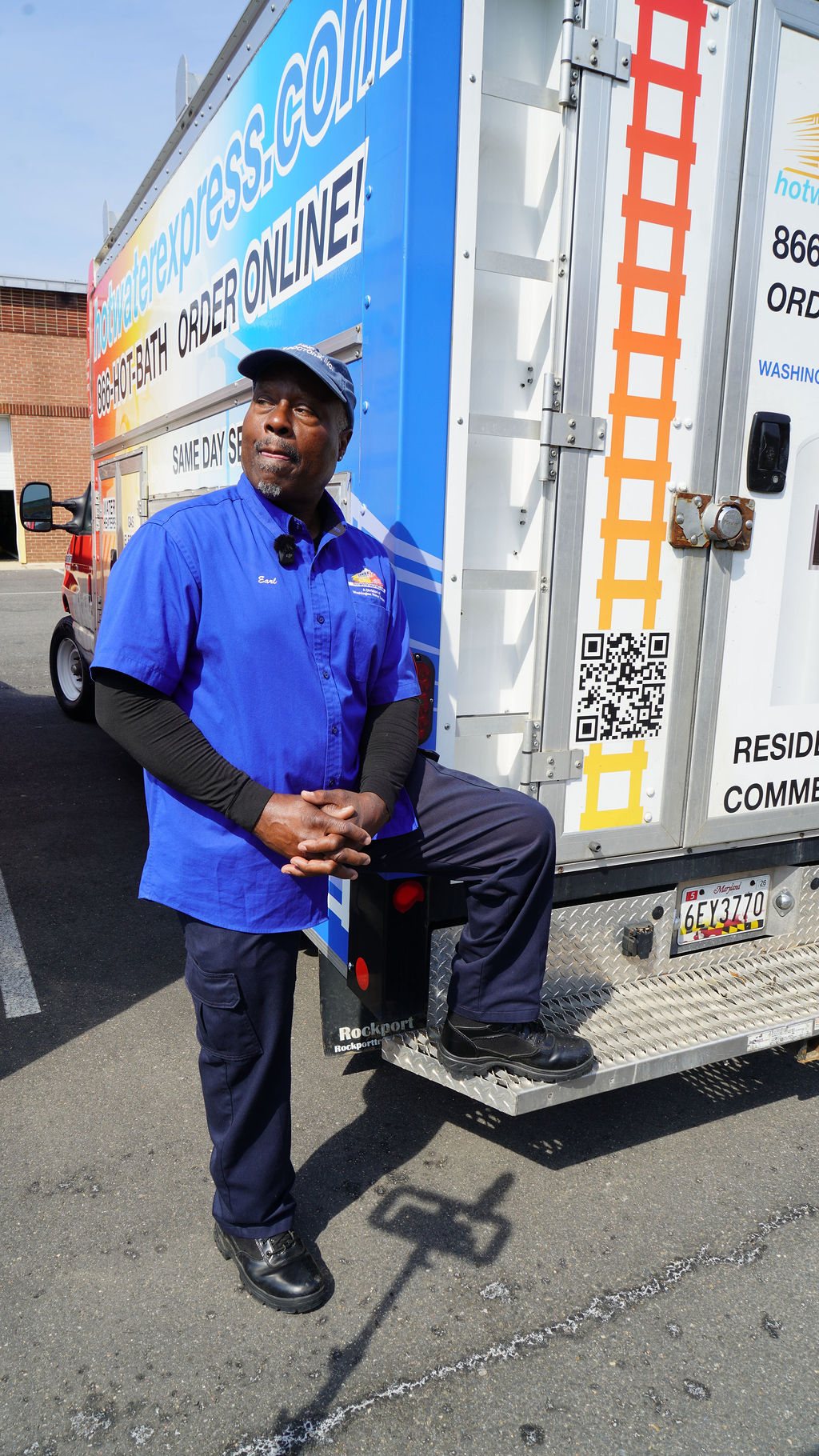 Earl Campbell, founder of Hot Water Express, standing on the step of the branded service truck