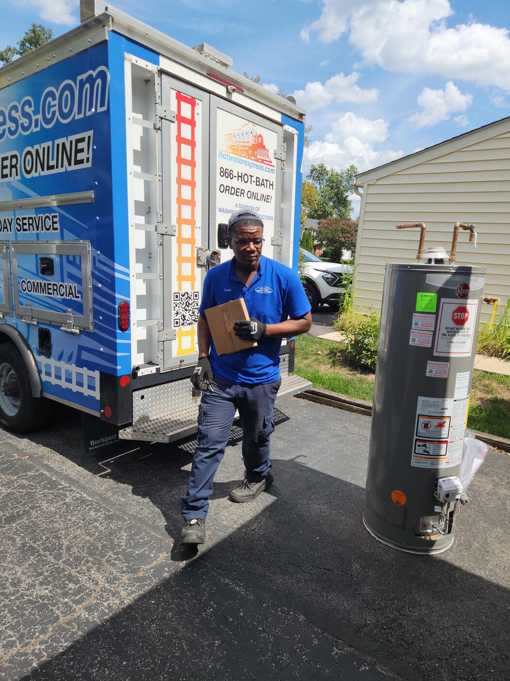 Hot Water Express technician beside the branded truck and removed water heater
